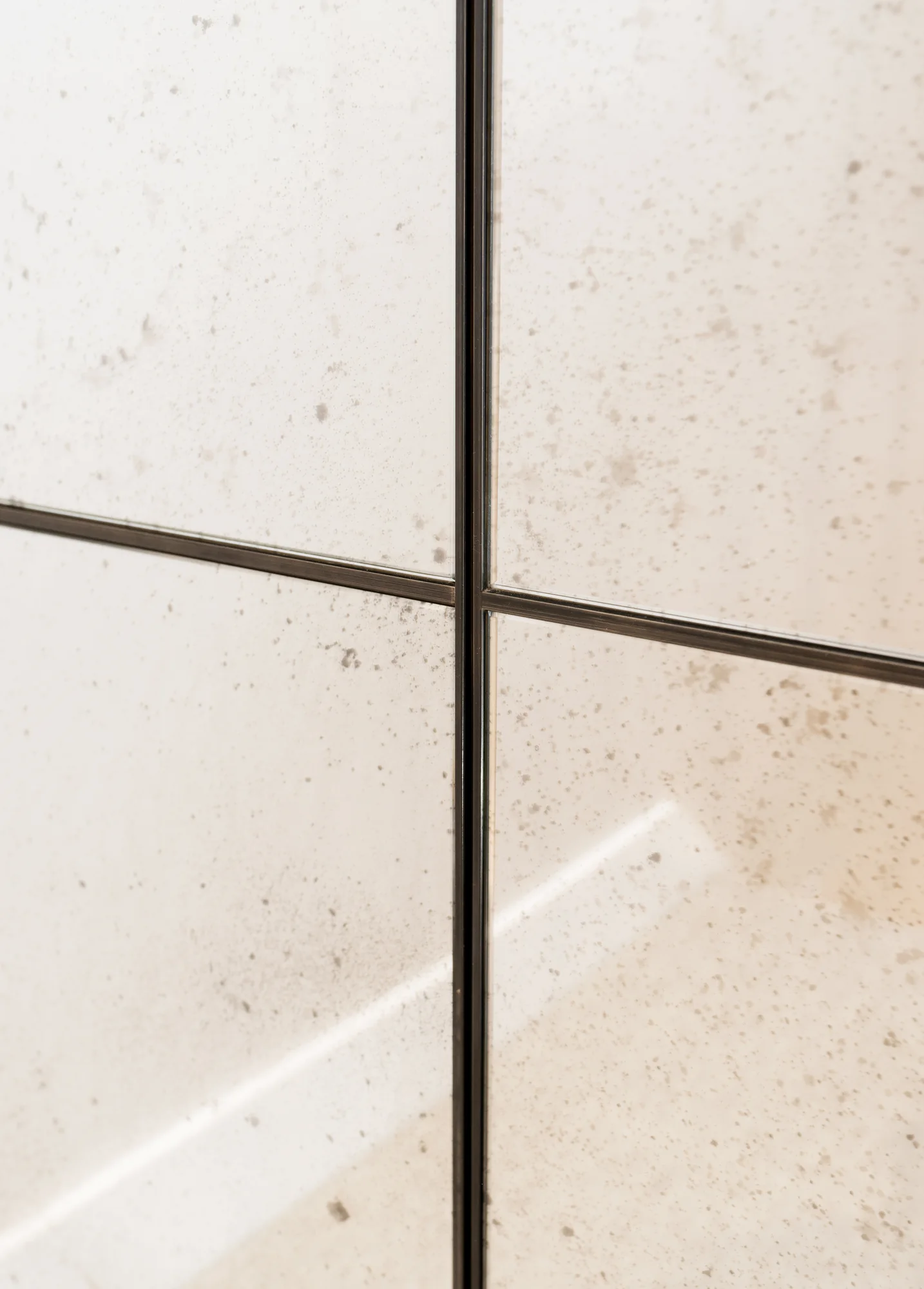 Close view of the aged mirror surface and narrow dark panel divisions