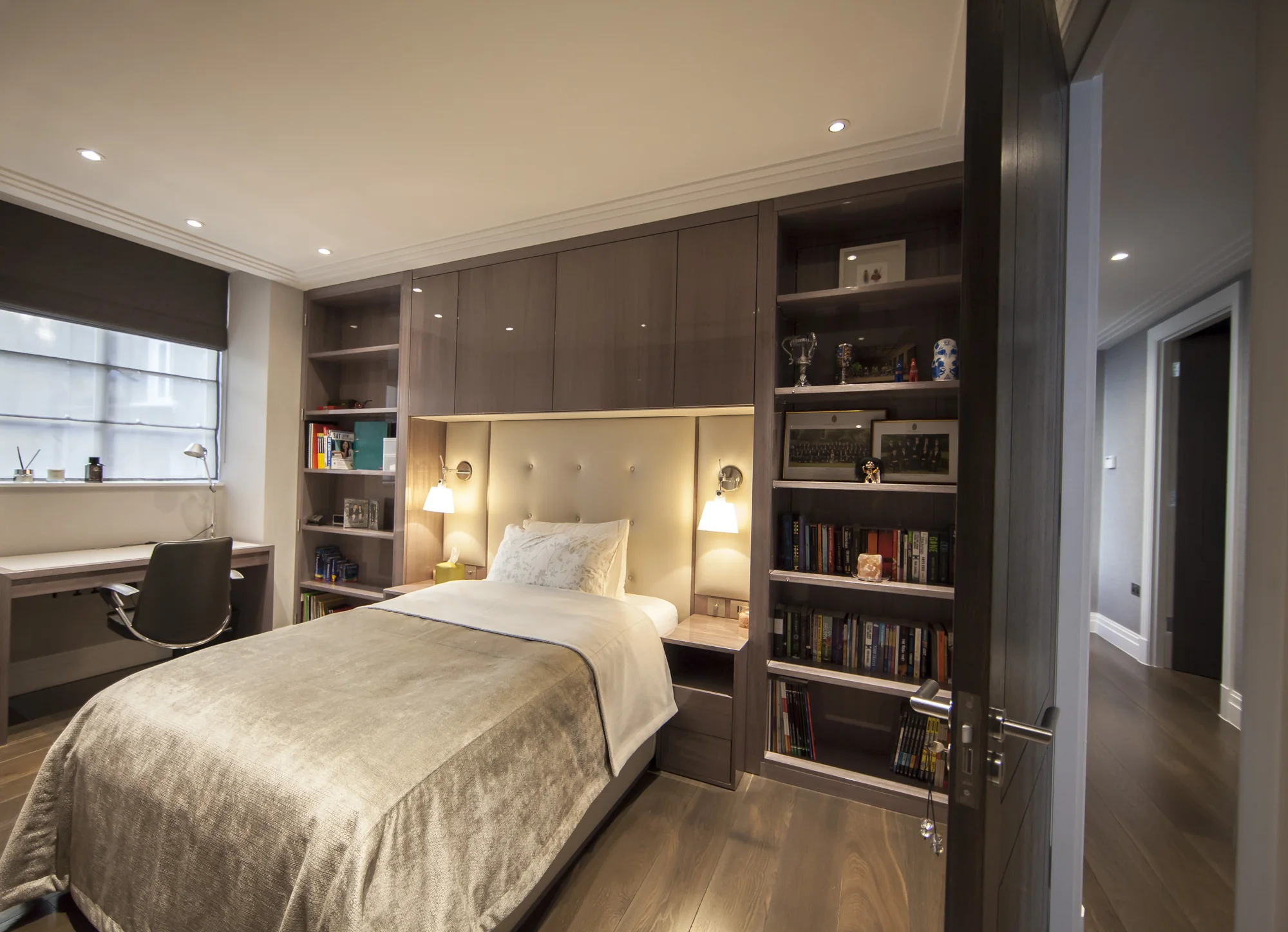 Full fitted bed wall with tall bookcases, overhead cupboards and bedside storage