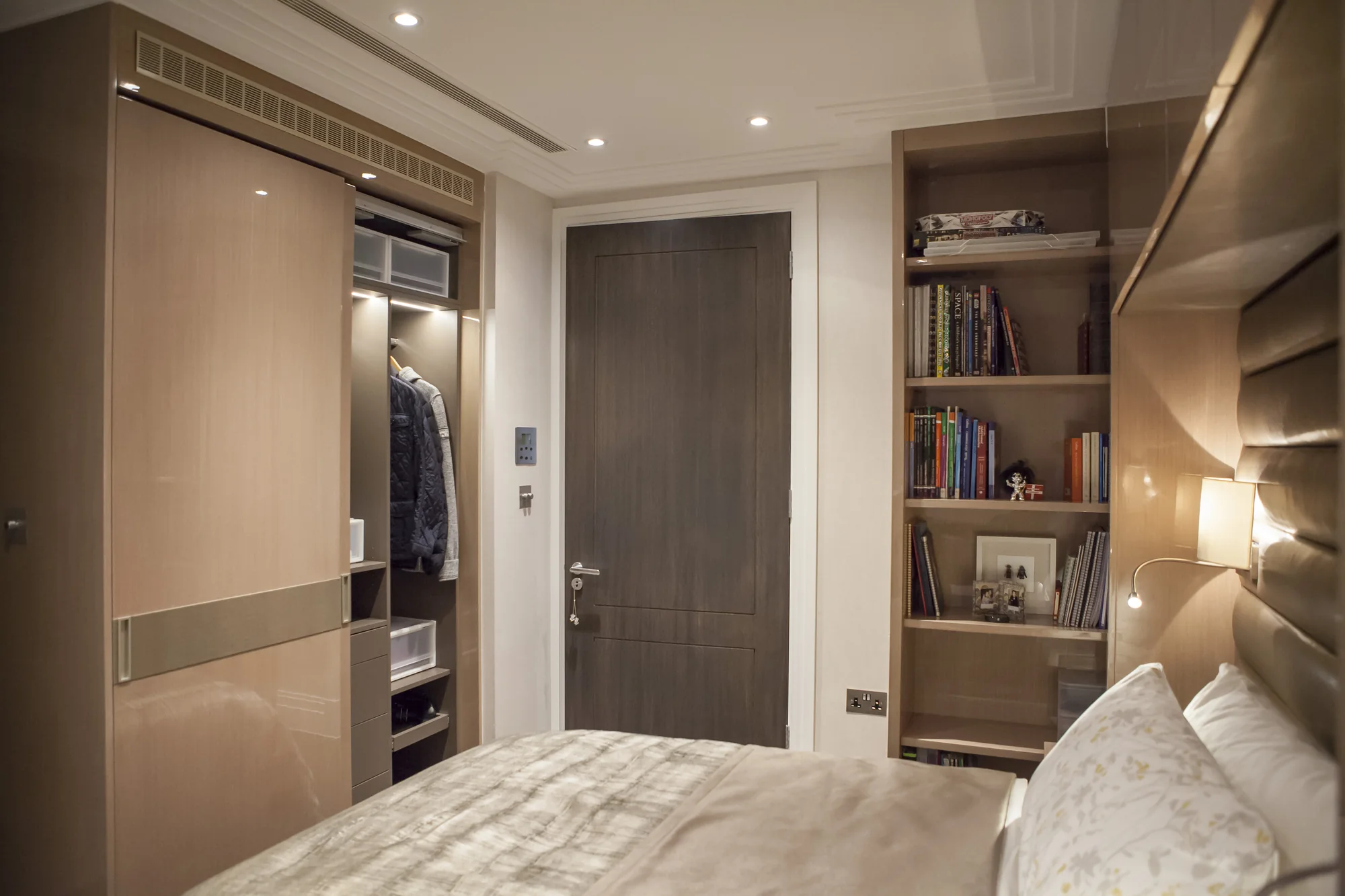 Bedroom view showing the padded bed wall, bookcase and adjacent fitted storage