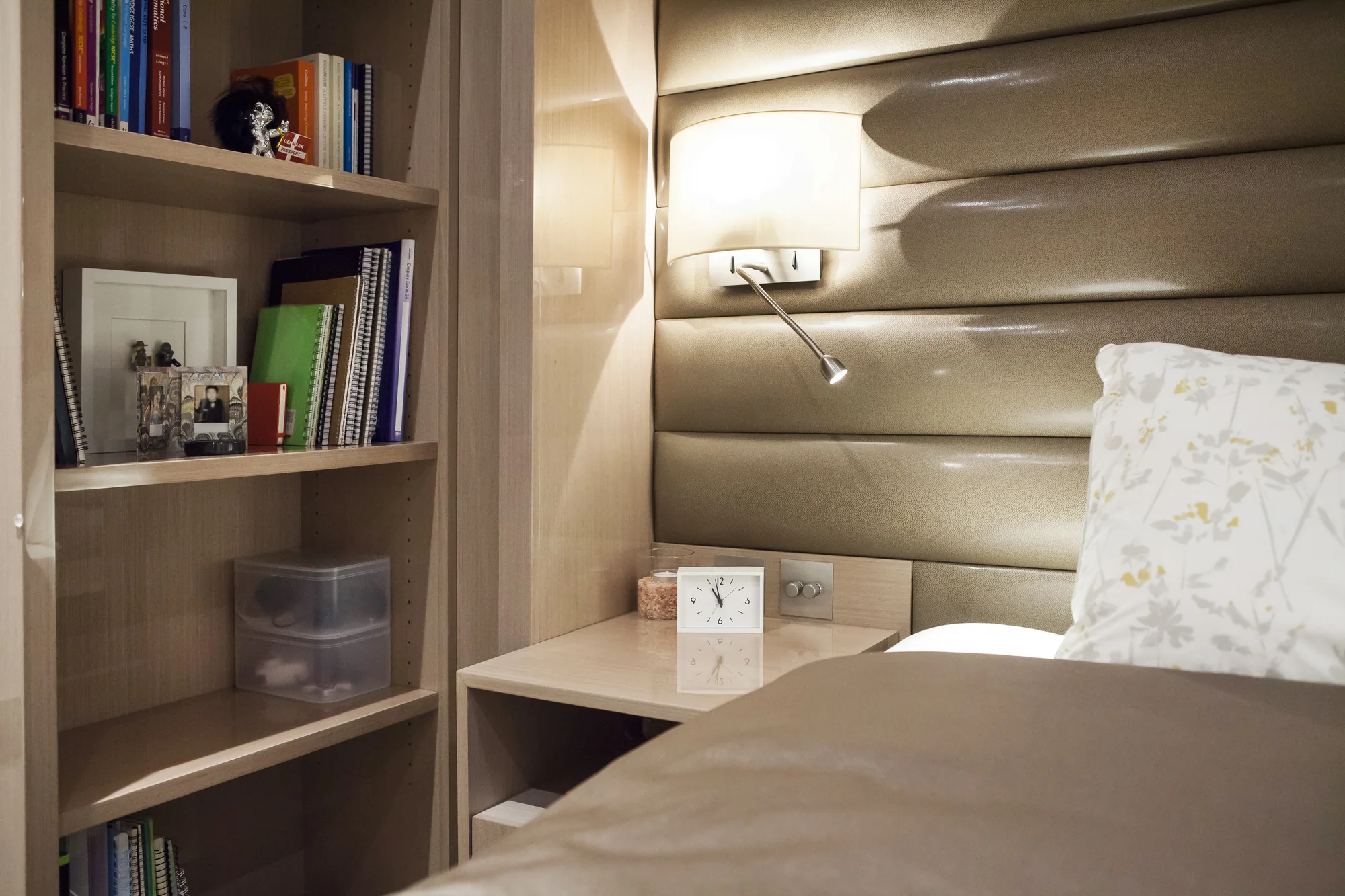 Open bookcase and bedside surface beside the curved padded headboard
