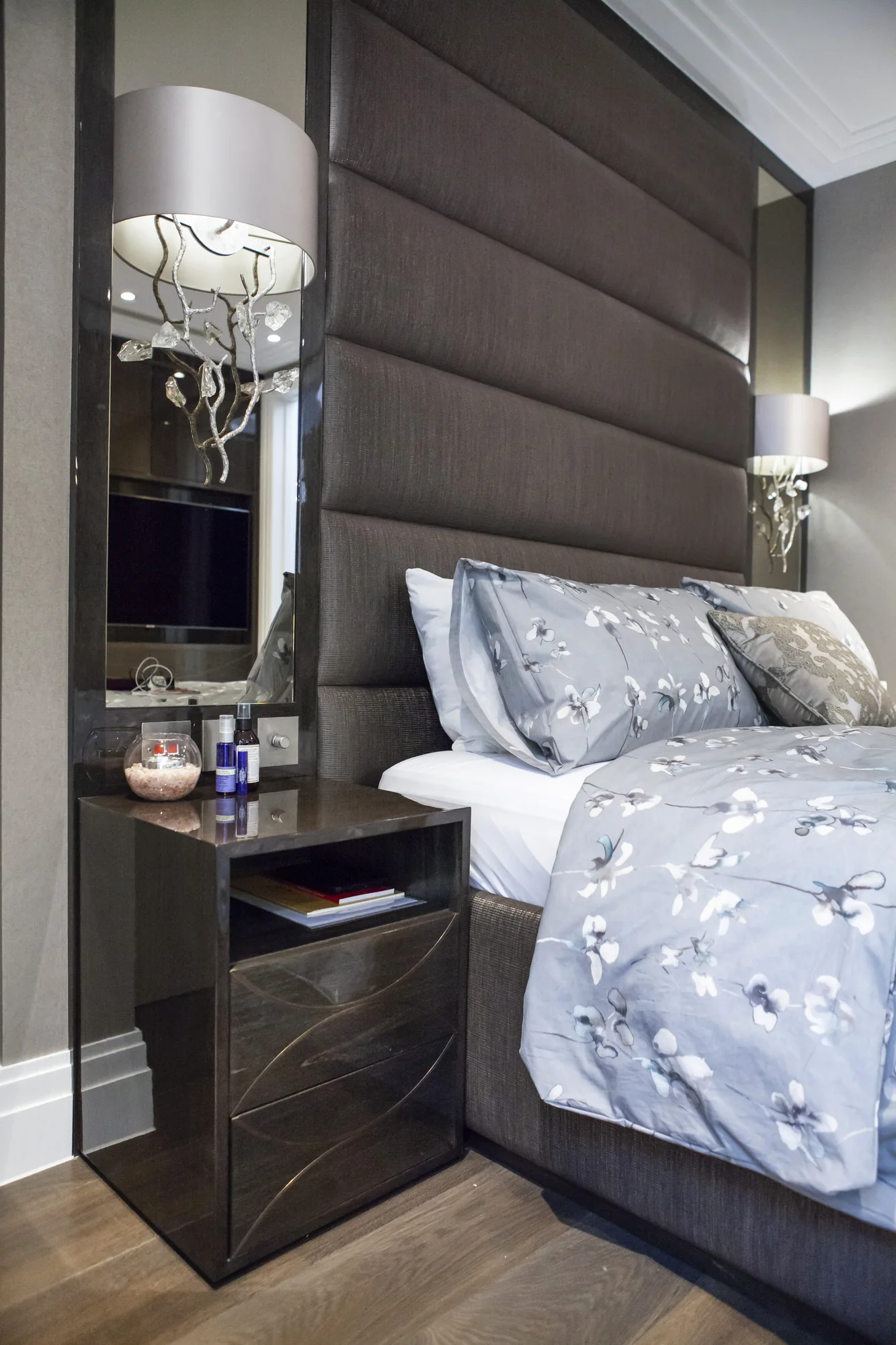 Bedside cabinet with its upper drawer open beside the padded headboard
