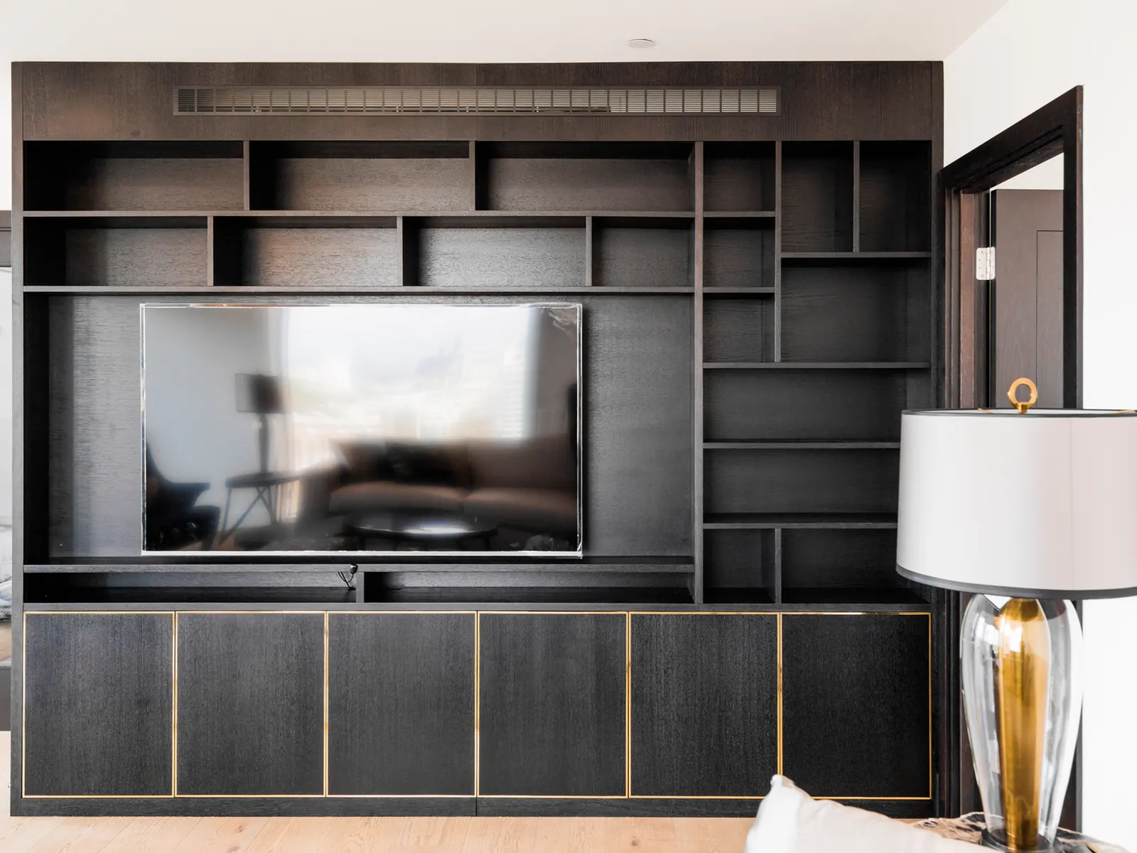 Front view of full-height black oak-grain media wall with integrated television
