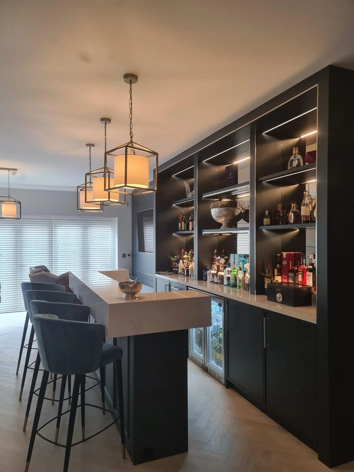 Side view along the home-bar counter towards its illuminated display wall.