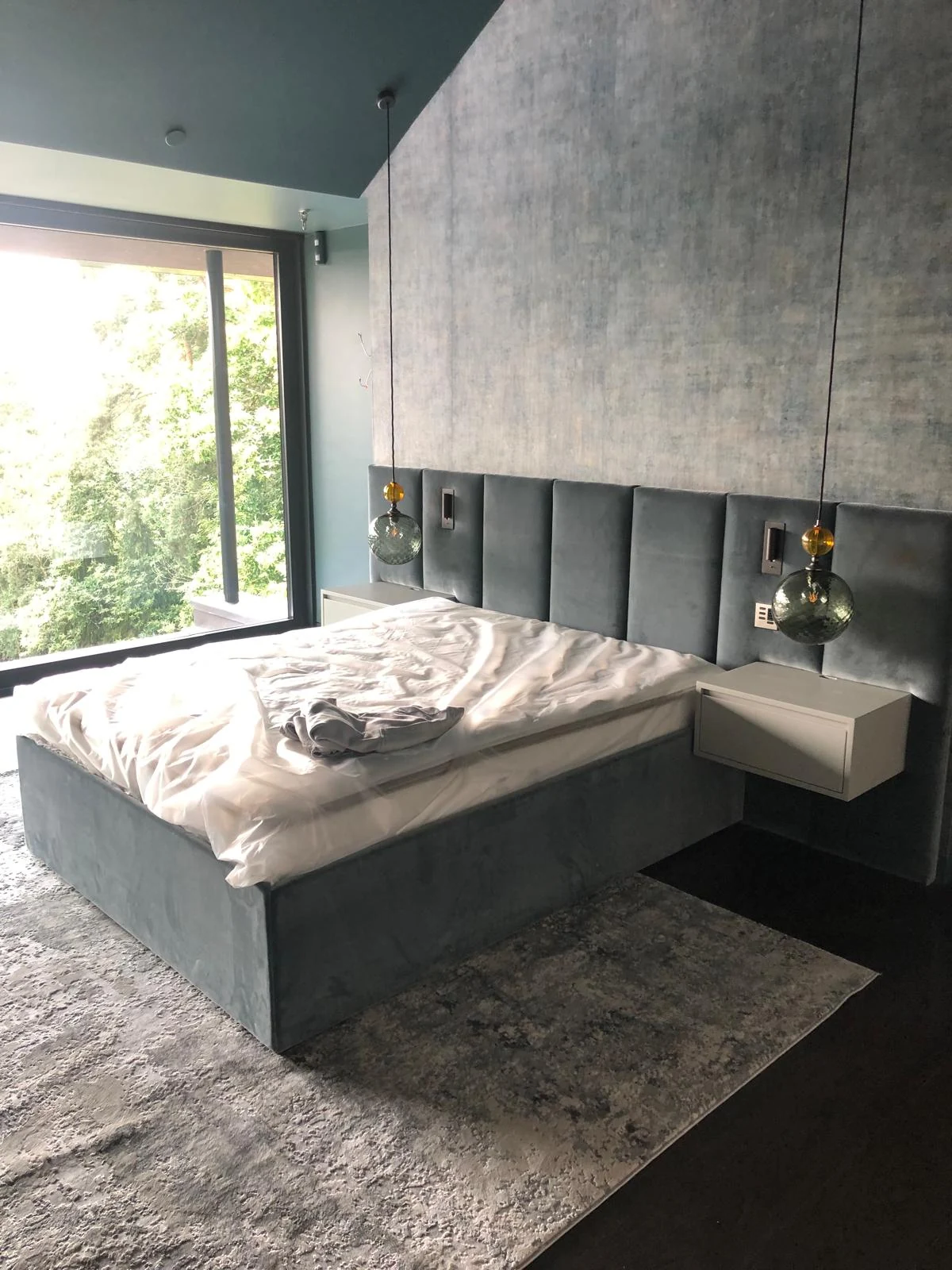 Bedroom with an upholstered headboard, floating bedside cabinet and wall-length upper panels.
