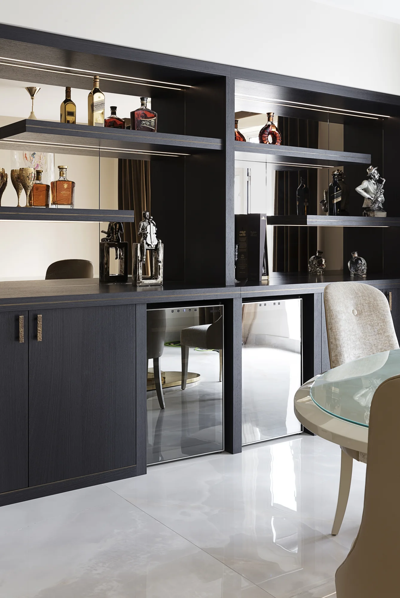 Angled view of illuminated shelves, lower cupboards and glazed drinks storage