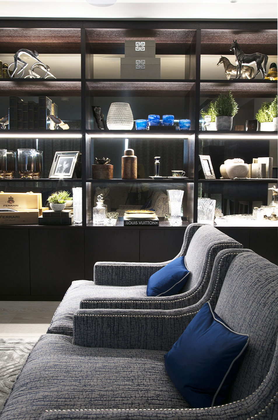 Illuminated dark wood-grain shelves beside the living-room seating