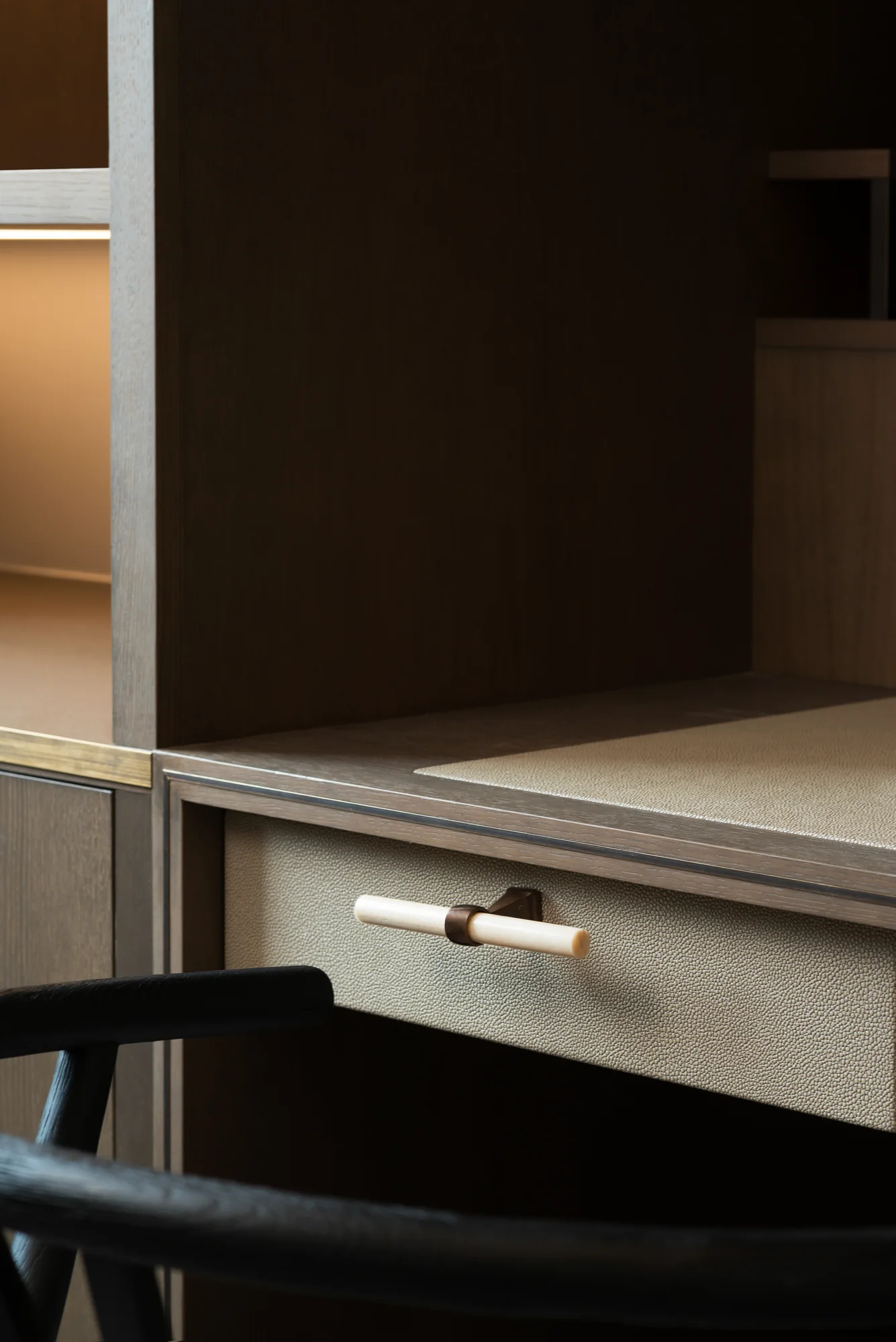 Textured desk drawer front, small metallic handle and fine worktop edge detail