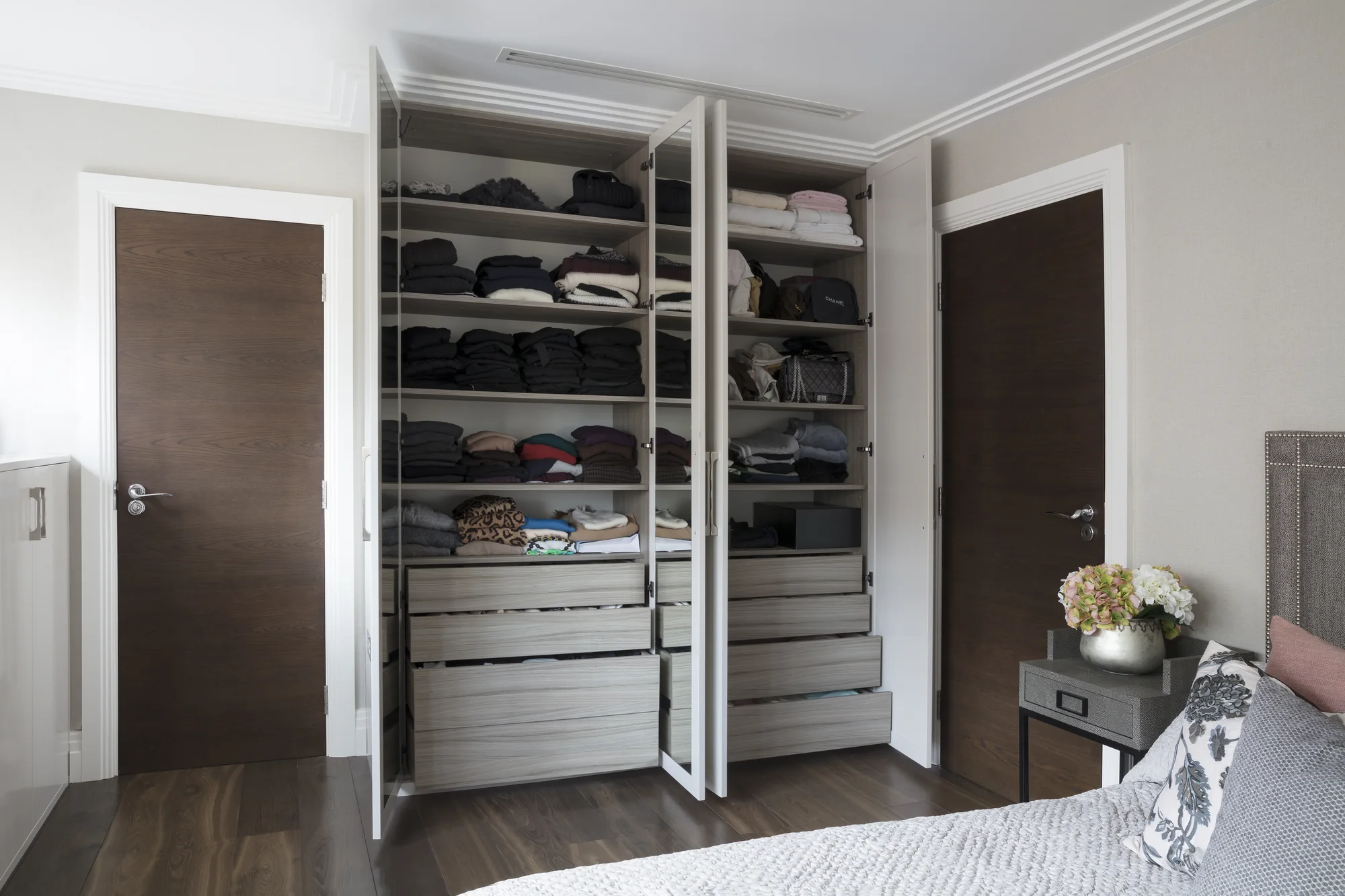 Open wardrobe doors showing fitted shelves and drawers