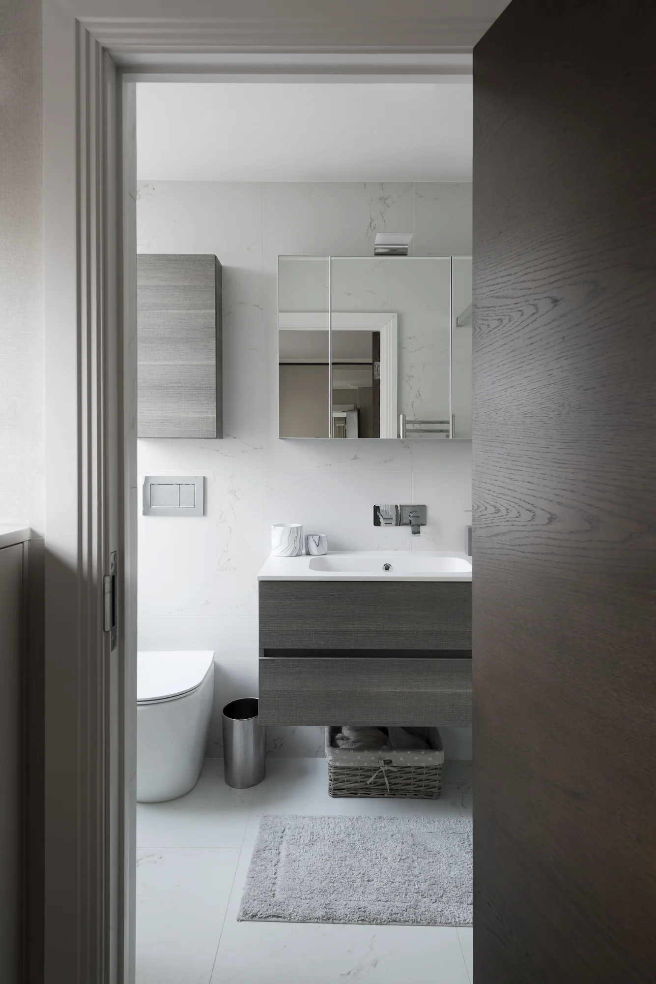 Doorway view of the dark grain vanity and mirrored bathroom storage