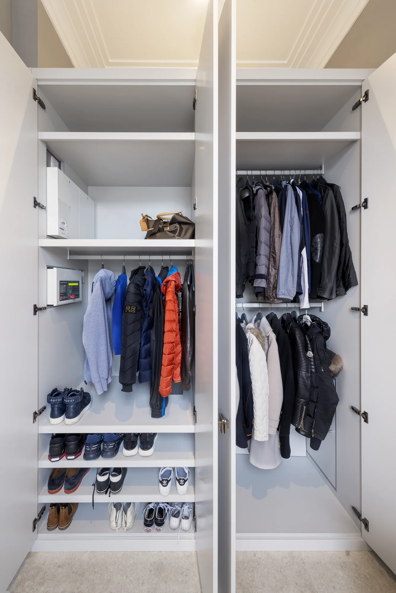 Open entrance wardrobe showing hanging rails, upper shelves and rows of shoe storage