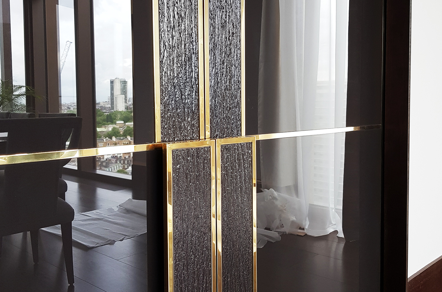 Close-up of polished brass line intersections on dark panelled doors