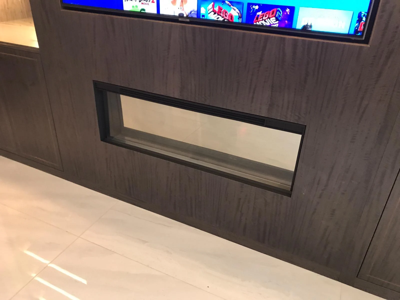 Detail of the inset fireplace within the wood-grain media-wall panel.