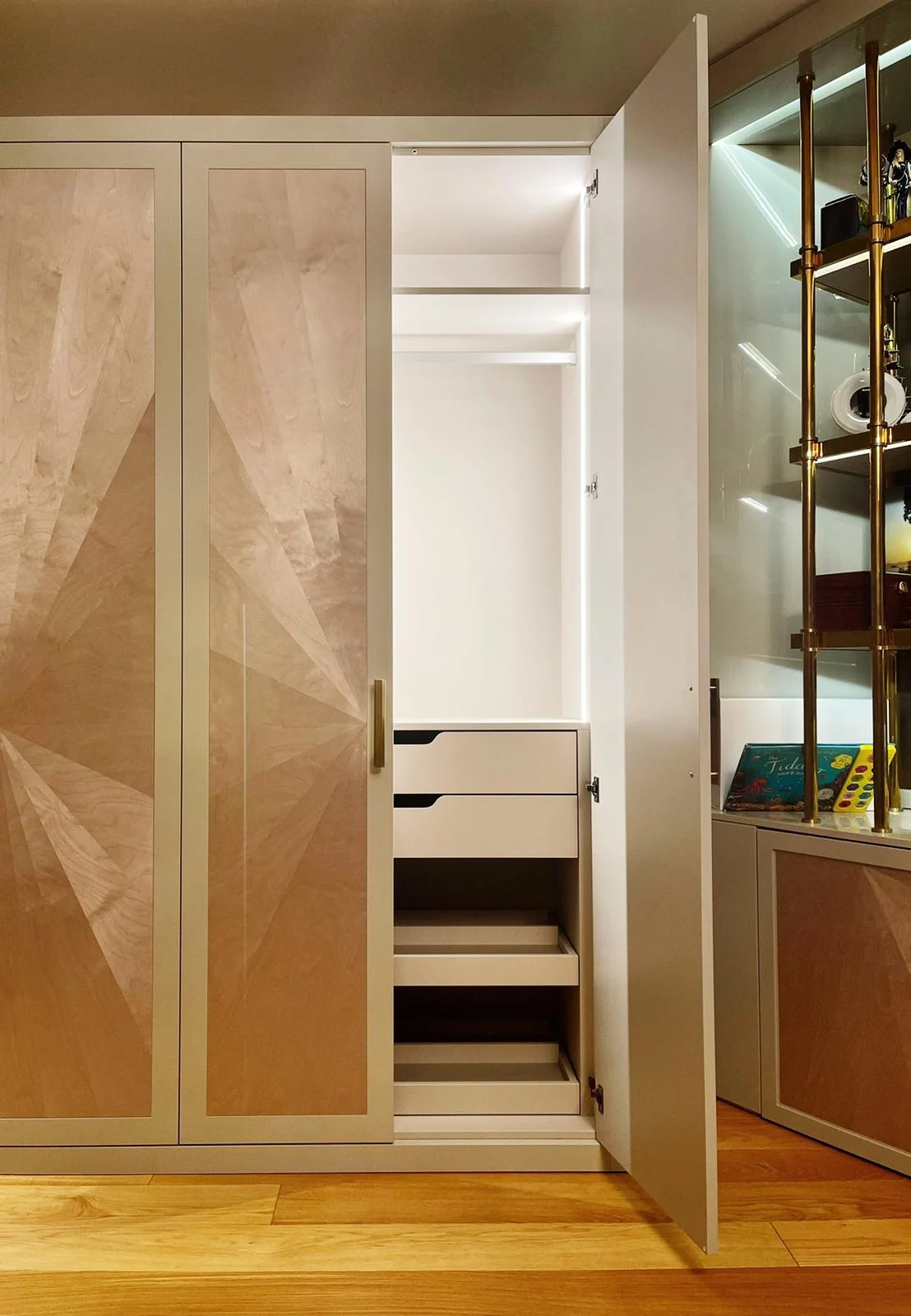 Sunburst-panel wardrobe with one door open to show internal drawers and hanging storage.