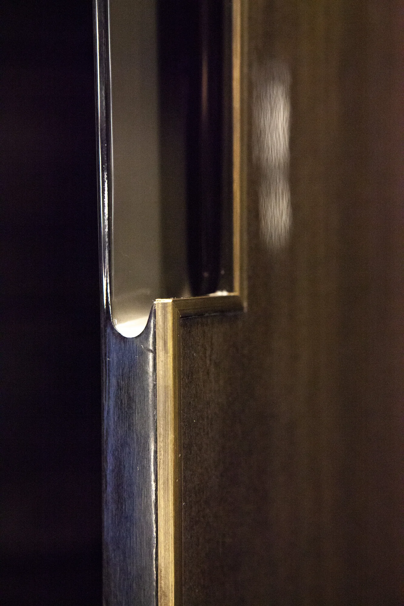 Recessed metallic fitting at the edge of the dark wardrobe panel