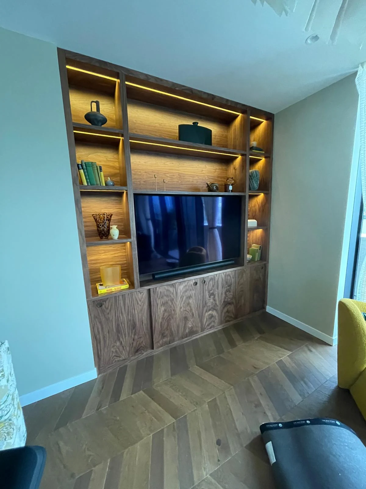 Warm-lit timber media unit with a central television and closed lower storage.