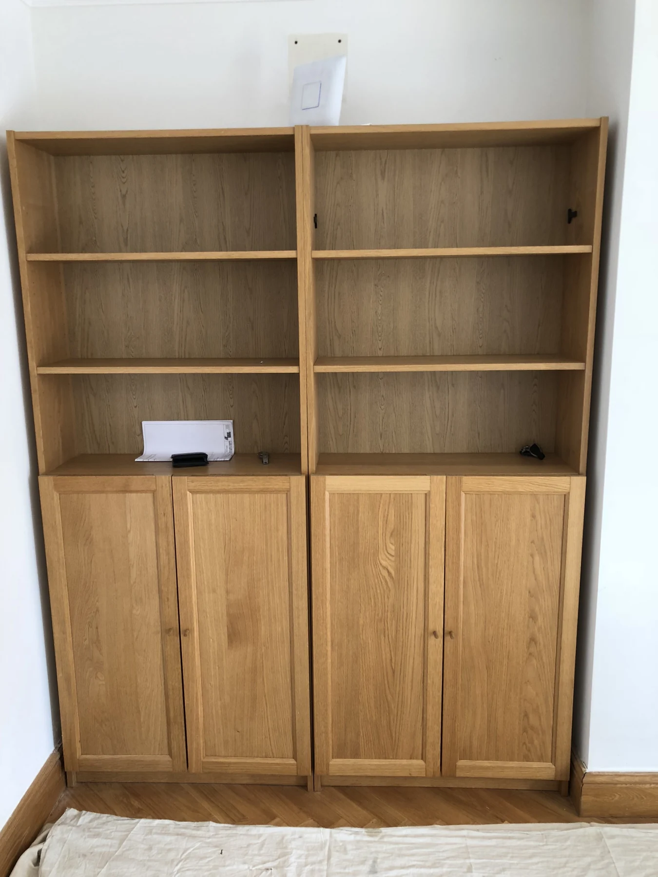 Wood-grain alcove bookcase with open shelves and lower framed cupboards.